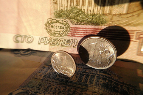 Рублёвые монеты стоят на сторублёвой купюре в тёплом солнечном свете крупным планом 