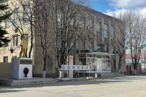 Здание районного суда в небольшом городе, перед входом памятник и голые весенние деревья 