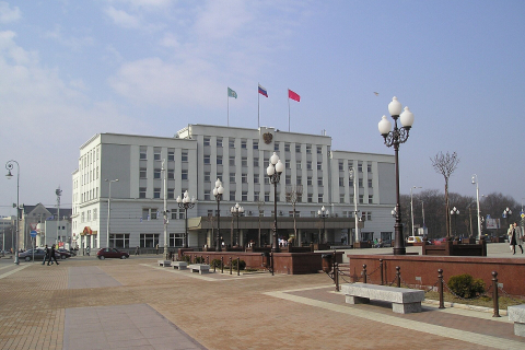 Здание администрации Калининграда с флагами и фонарями на площади Победы в ясный день 