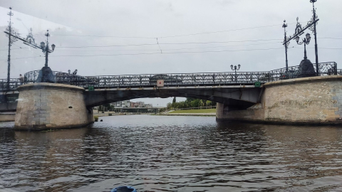 Металлический мост с коваными фонарями через реку в пасмурный день в Калининграде 