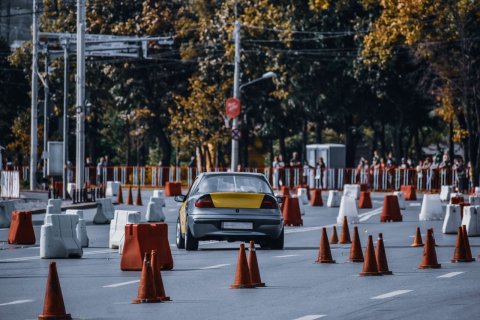 Машина проходит площадку с оранжевыми конусами и бетонными блоками на автодроме 