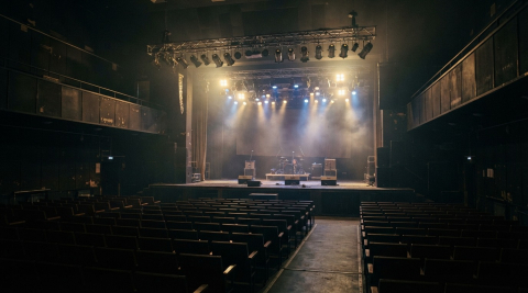 Пустой клубный зал со сценой, ферма с прожекторами светит в дымке 