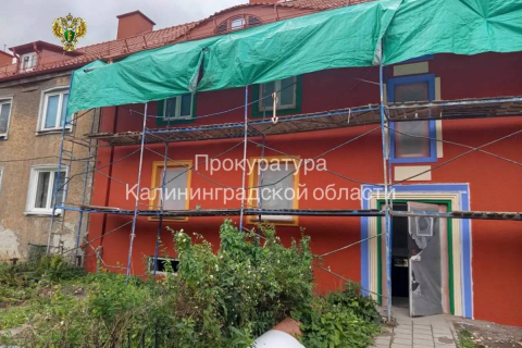 Фасад старого кирпичного дома с разноцветными секциями на улице в Черняховске 