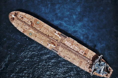 Длинный танкер в открытом море, вид сверху на палубу и тёмно-синюю воду 