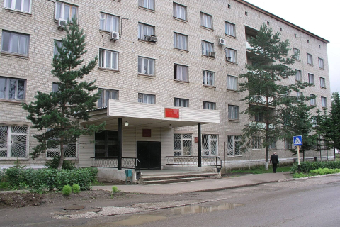 Вход в городской суд под козырьком в многоэтажном доме среди сосен 