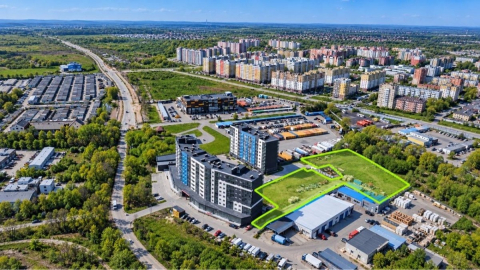 Огороженный пустой земельный участок на фоне многоэтажной жилой застройки в Калининграде 