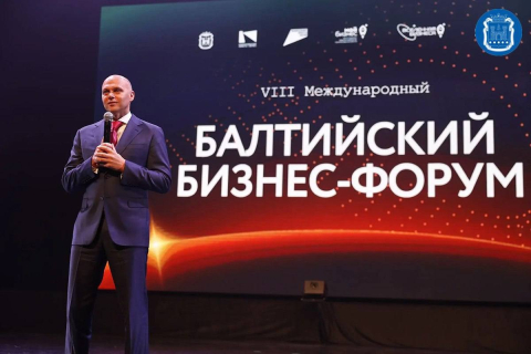 Сцена и зал делового форума с участниками и флагами на мероприятии в Калининграде 