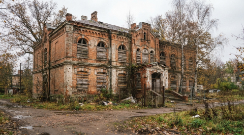 Старинное кирпичное здание бывшей лечебницы с заколоченными окнами в Знаменске под Калининградом 