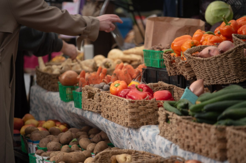 Плетёные корзины с перцем, картофелем и огурцами на рыночном прилавке 