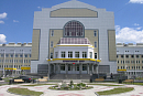 Вход в перинатальный центр с полукруглым стеклянным фасадом и клумбой перед крыльцом 