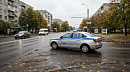Серебристый автомобиль полиции с синими маячками на крыше едет по городской улице 