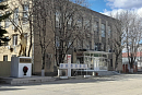 Здание районного суда в небольшом городе, перед входом памятник и голые весенние деревья 