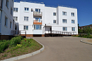 Новый белый трёхэтажный жилой дом с пандусом у входа и свежим асфальтом 