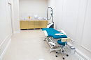 Процедурный кабинет с бирюзовой кушеткой, стулом и шкафами вдоль стены 
