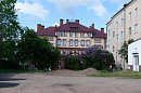 Старое здание с красной крышей за цветущей сиренью в Черняховске 