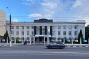 Светлое административное здание отделения Центробанка за оградой, перед ним улица с машиной 