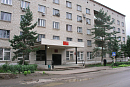 Вход в городской суд под козырьком в многоэтажном доме среди сосен 