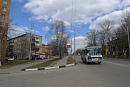 Маленький автобус едет по пустой улице небольшого города мимо пятиэтажек весной 